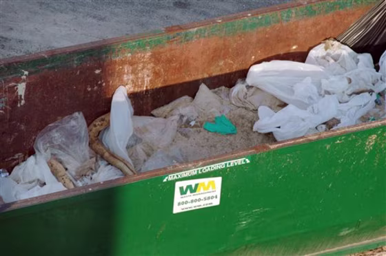Soiled, oil-absorbing boom and other debris sit in an open, improperly lined waste container&nbsp;in Orange Beach, Ala., on&nbsp;June 17.